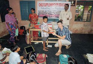 Public policy graduate student Jonathan Slakey helps distribute donated school supplies to a class in India. He is interning for the Association of Relief Volunteers.