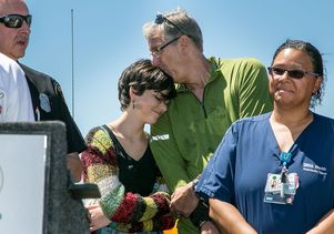 Robert Kilroy and his daughter Emily hug at a press conference, attended by Jena Lewis, a nurse and prehospital care coordinator at Reagan UCLA Medical Center, and others who cared for him.