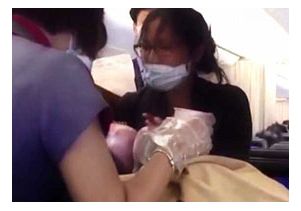 Dr. Angelica Zen (right) holds the newborn after tending to the mother for 3 1/2 hours. Passengers applauded the birth.