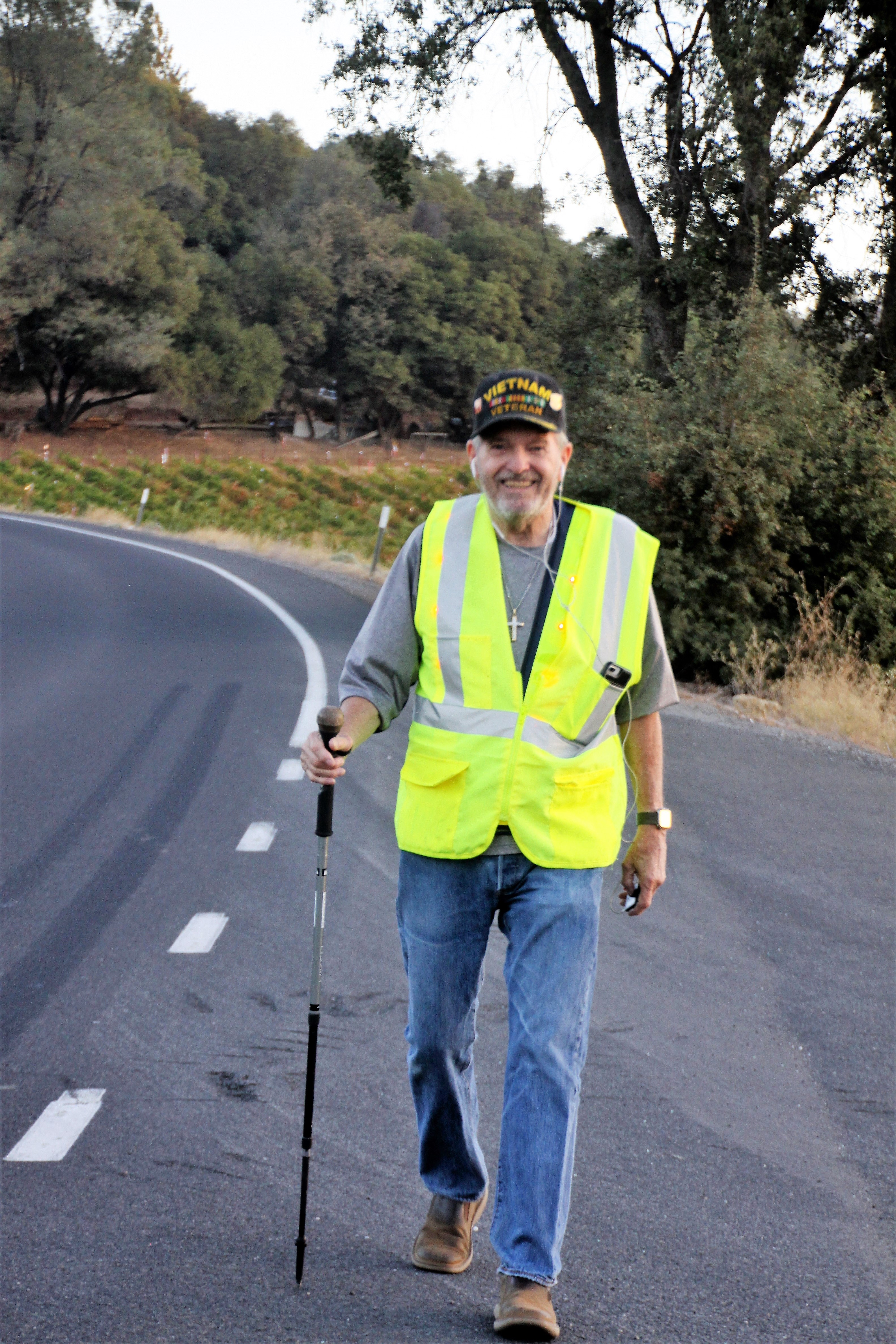 Caption Ric Ryan wearing a high-visibility vest walking along a road.