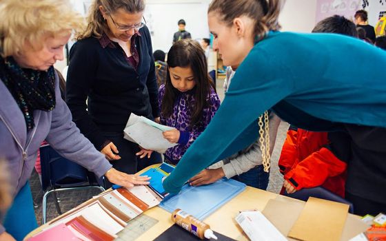 UNM architecture student Taylor Small (r.) arranges students' portfolios.
