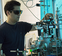 Graduate student Aram Gragossian working in an optics lab Ph.D. student working in optics lab