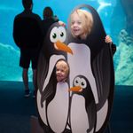 Two children are all smiles as they stand with a penguin cutout in front of the beluga habitat at Georgia Aquarium on Jan. 30. Kids pose with penguin cutout
