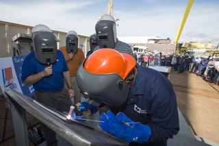 Roderick P. Funches, a structural welder at Ingalls Shipbuilding, welds the initials of Julie Sheehan on a ceremonial keel plate that will be welded to WMSL 755, the National Security Cutter named in honor of her great uncle, Douglas A. Munro. Photo by Andrew Young/HII National Security Cutter Munro Keel-Laying