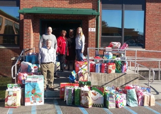 Izzie Brown (second from right), principal of Carver Elementary School in Newport News, accepts donations from AMSEC employees (left to right) Dewey Stinson, Wayne Hunley, Pam Ponton and Kinsey Hall. AMSEC photo AMSEC Holiday Giving