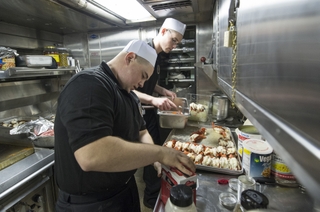 Sailors prepare surf and turf as the first meal for the 146-member crew that will serve aboard the submarine John Warner (SSN 785). Photo by Ricky Thompson/HII Sailors Prepare First Meal on John Warner