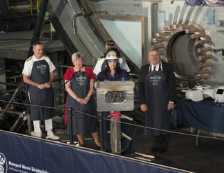 Heather Johnson shows Diane Donald’s welded initials to more than 500 guests at the Indiana keel-laying ceremony. Behind her are (left to right) Vice Adm. Michael J. Connor, commander, Submarine Forces; sponsor Diane Donald; Stephen Trautman, deputy director, Naval Nuclear Propulsion Program; and Matt Mulherin, president, Newport News Shipbuilding. Photo by Ricky Thompson/HII Heather Johnson Shows Welded Initials
