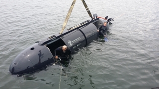 Chloe Mallet (right), an ocean engineer at HII’s Undersea Solutions Group (USG) subsidiary, prepares to crew and drive the Proteus dual-mode underwater vehicle with USG Vice President Ross Lindman (left). Mallet and Andrea Raff (not pictured), a mechanical engineer at USG, are the first women to crew and drive a swimmer delivery vehicle. Photo by Joe Colamaria/HII Undersea Solutions Group's Proteus Operated by Female Diver