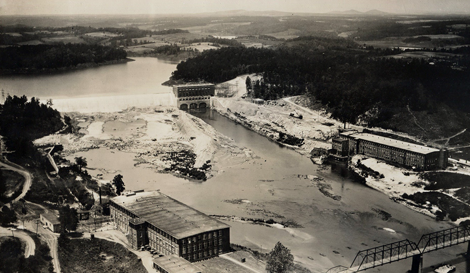 The concrete gravity Rhodhiss dam and overflow spillway is 1,517 feet long and 72-feet high. Other than normal generation and transmission upgrades, the dam and powerhouse have undergone minimal alterations since the plant began operating in 1925. In 2001, anchors were drilled in the spillway and flood walls were added to the north and south abutments of the dam to meet new federal flood standards. 2018-0105-rhodissExterior1926