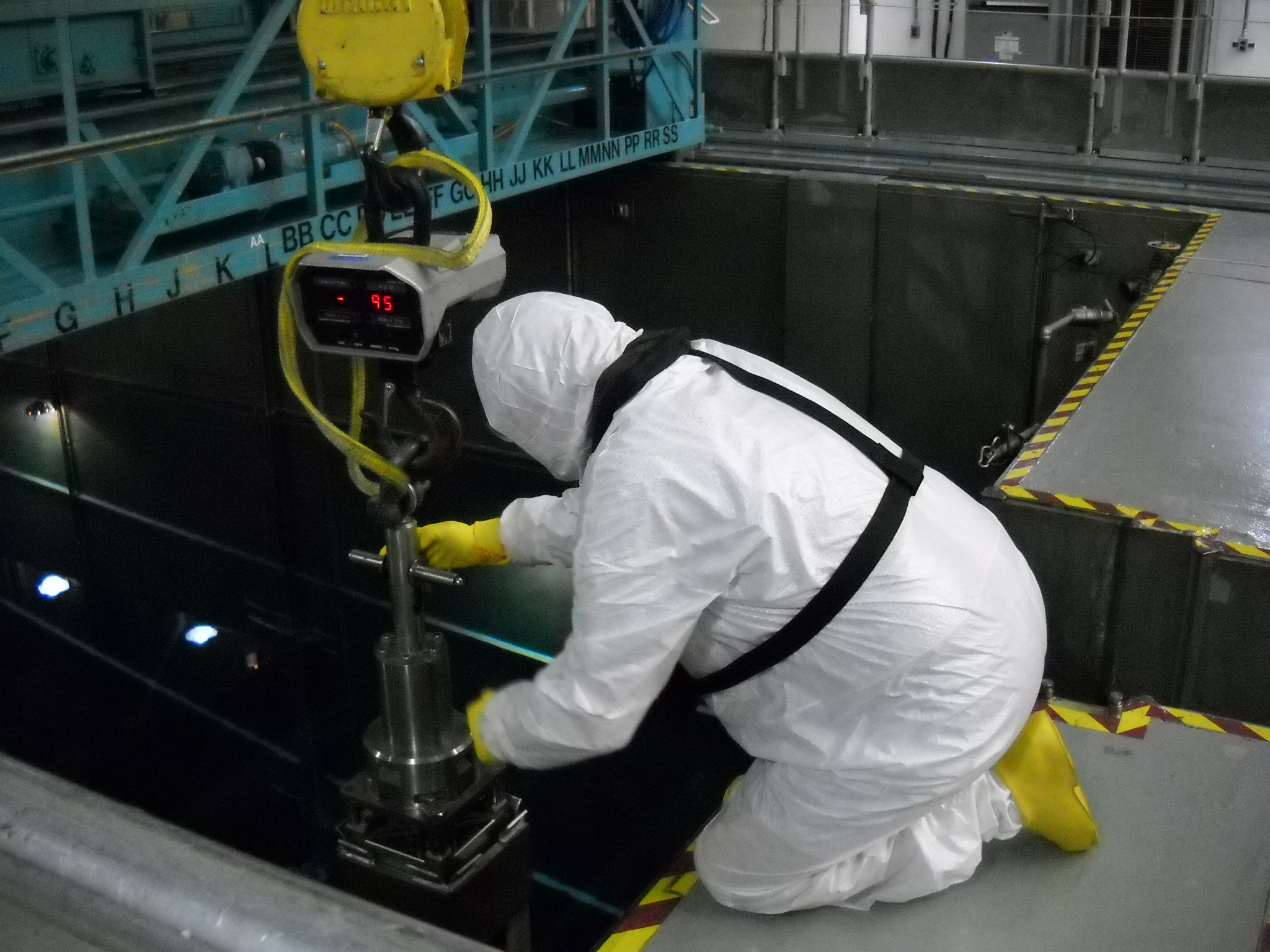 A member of the fuel team helps guide a new fuel assembly into the used fuel pool. A member of the fuel team helps guide a new fuel assembly into the used fuel pool.